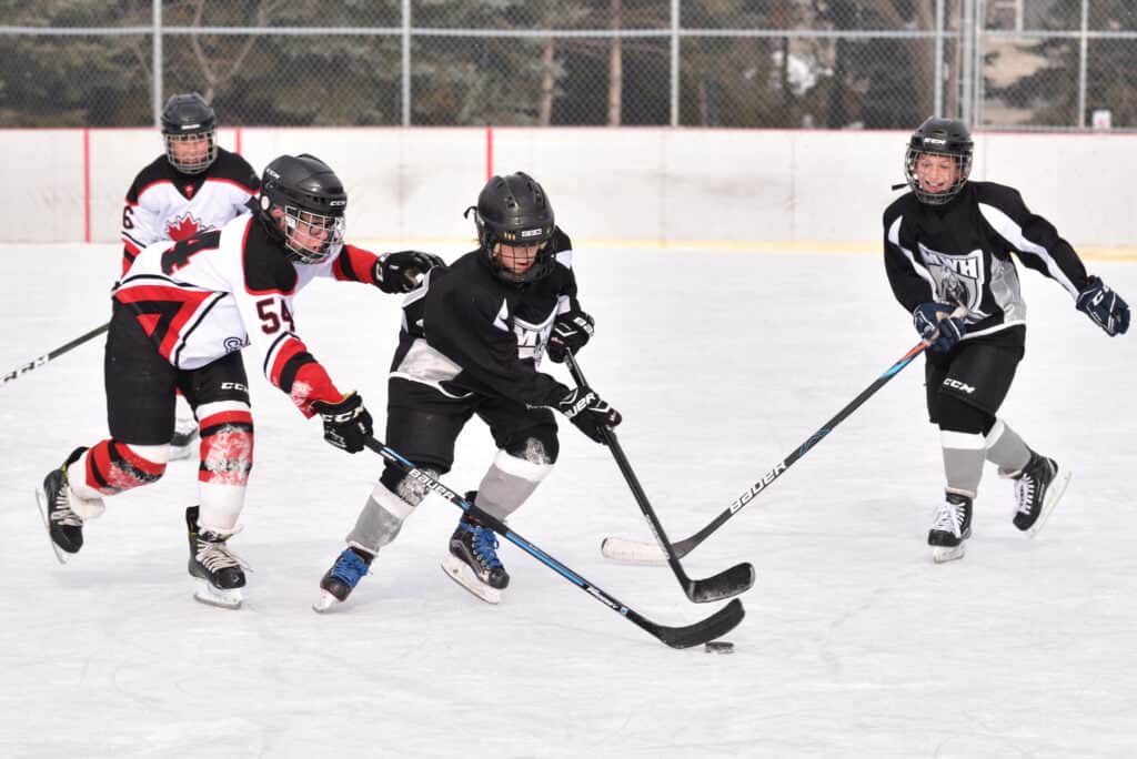 des enfants jouant au hockey sur une patinoire extérieure